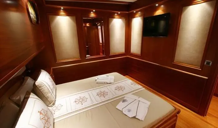 Inside Kaya Guneri 5 cabin shows wooden walls, bed, and folded towels