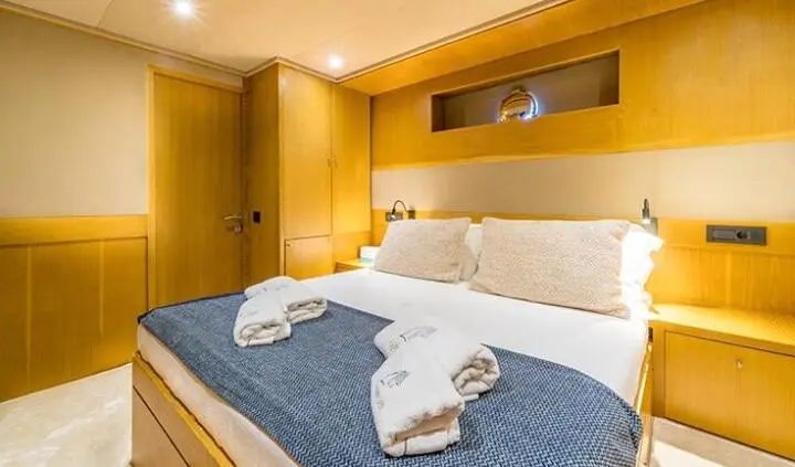 Queen bed with blue bedding and white towels in a cabin on Happy Days yacht