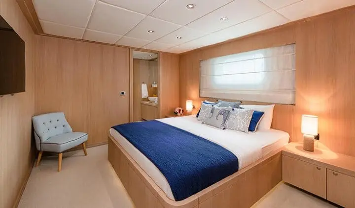 Grace cabin bedroom with queen bed, blue and white linens, wood-paneled walls
