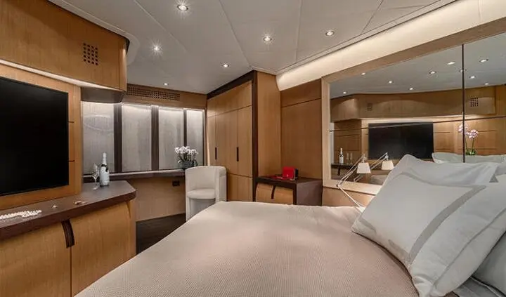 View of a luxurious yacht cabin with a king bed, leather seating, and warm lighting