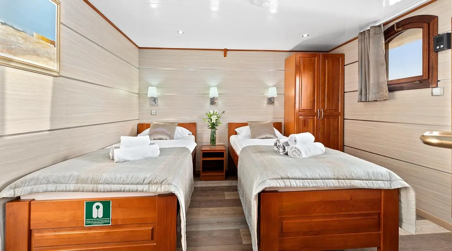 Karizma yacht deck view with twin beds, wooden furniture, and soft lighting in cabin