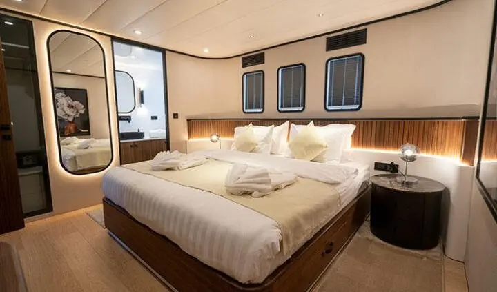 Master cabin with king bed, beige bedding, wood accents, ensuite area