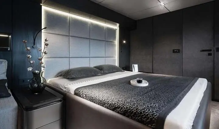 A luxury yacht cabin with two beds, dark bedding, and cabin window view