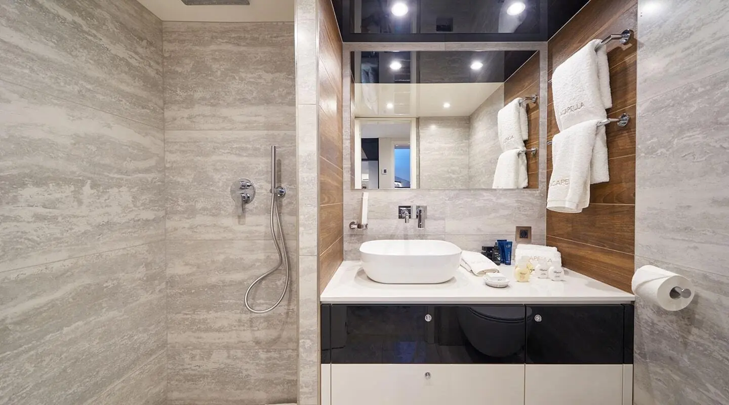 Acapella yacht bathroom with beige tiled walls, sink, mirror, and vanity.
