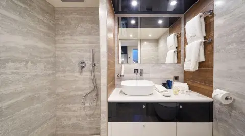 Acapella yacht bathroom with beige tiled walls, sink, mirror, and vanity.