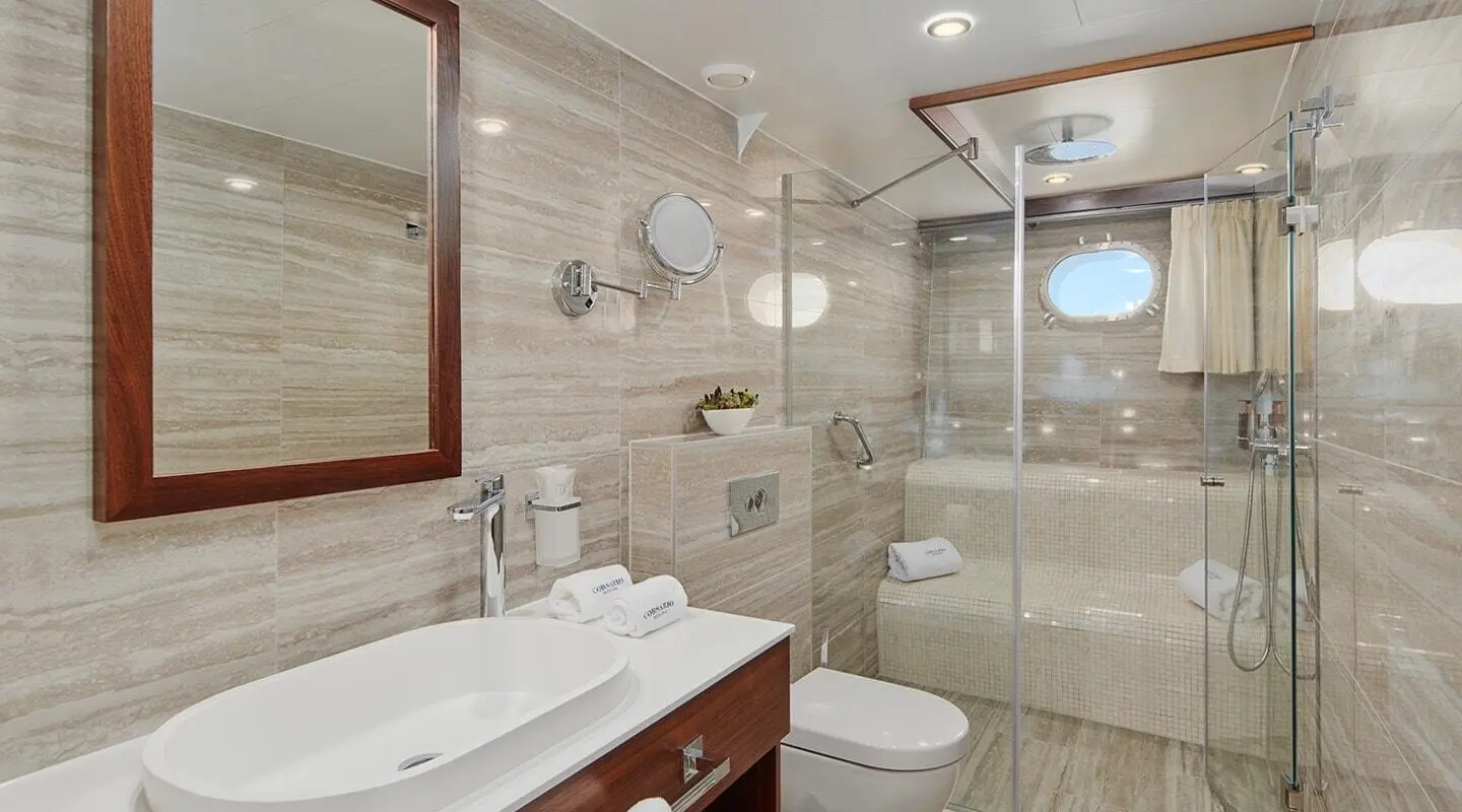 Luxurious yacht Corsario interior with glass shower, sink, and mirror vanity at sunset