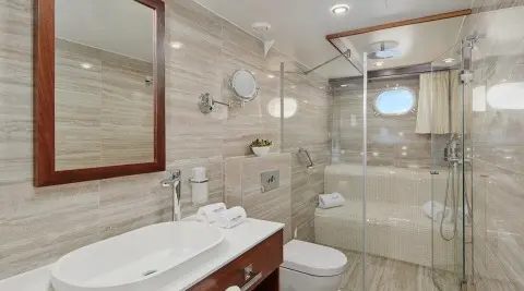 Luxurious yacht Corsario interior with glass shower, sink, and mirror vanity at sunset