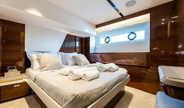 View of a king-size bed in a yacht cabin with portholes and wood paneling