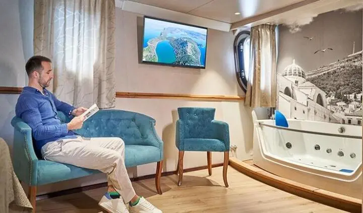 Casablanca yacht cabin with a king bed, striped headboard, and seating area