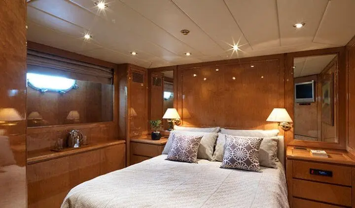 Idylle yacht cabin with king bed, wooden panels, bedside lamps, and pillows