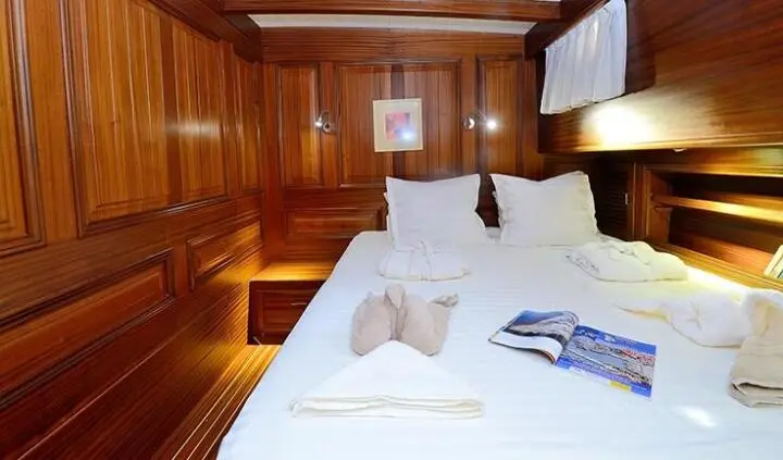 View of a yacht cabin with two single beds, wooden walls, and pillows