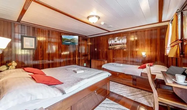 Cesarica yacht cabin interior with wooden cabinetry, beds, and red pillows