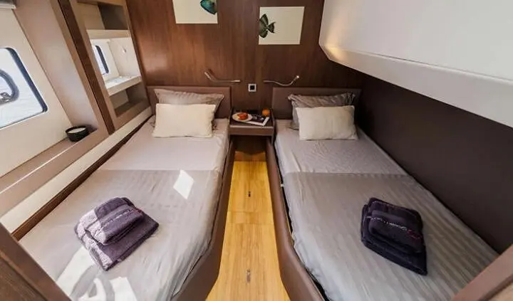 Twin cabin with two single beds and wood accents on a yacht interior