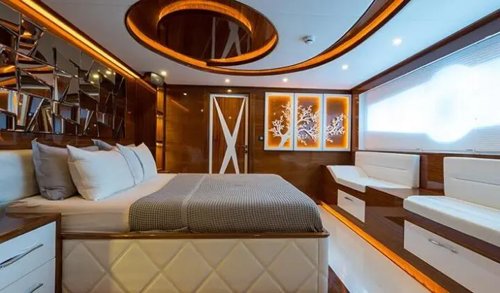 Gulet-style yacht cabin interior with bed, wooden panels, and framed shelves