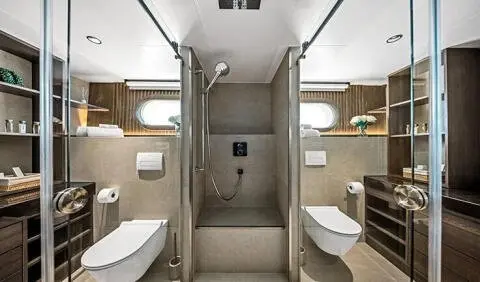 Master cabin with king bed, ensuite, wood panels, soft lighting, and angled seating areas