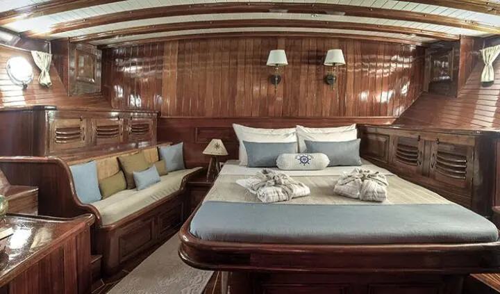 Master cabin with king bed, wood panels, and bedside lamps aboard Entre Cielos