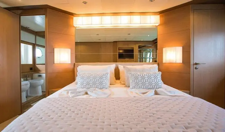 Luxurious master cabin with king bed, white linens, wood accents, and en-suite area