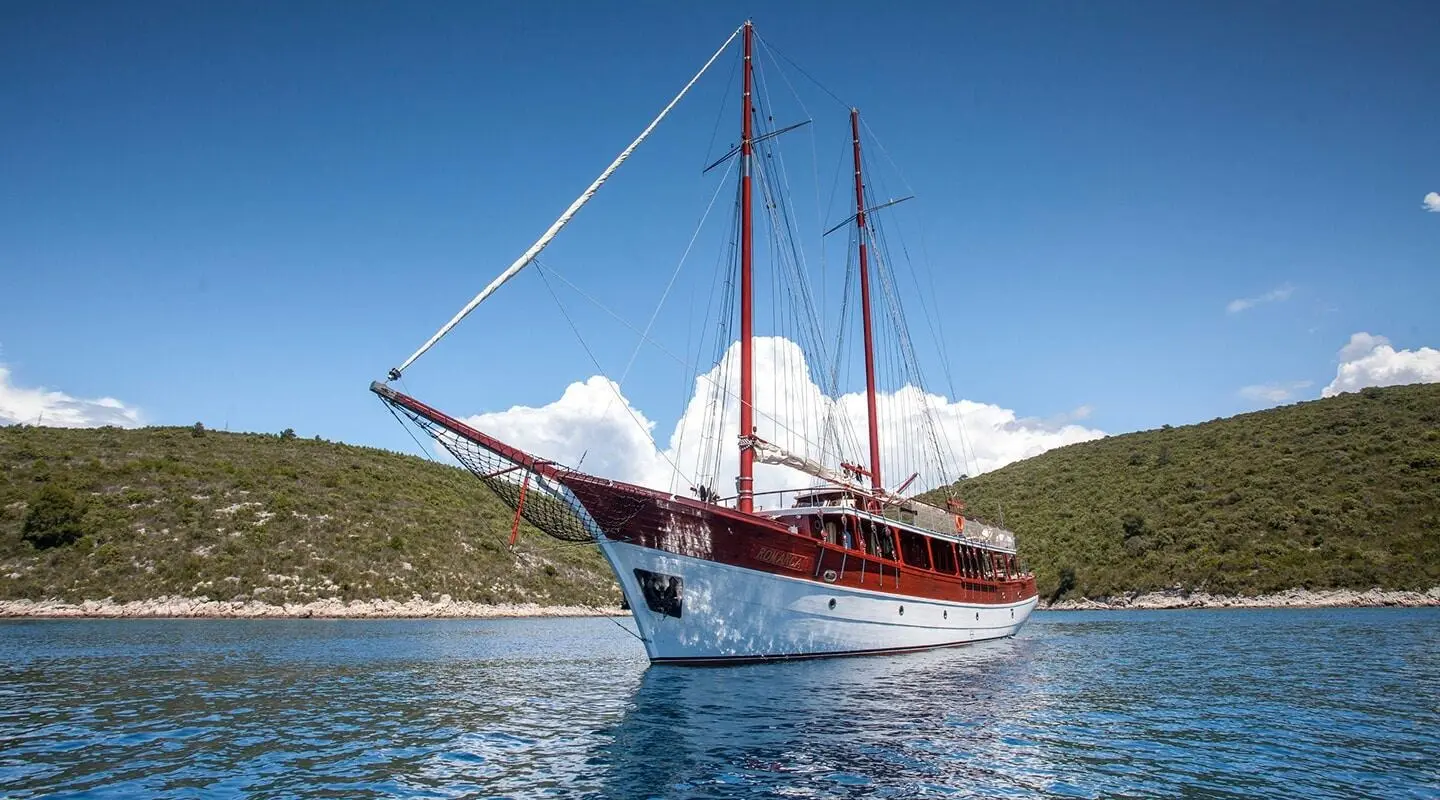 Romanca gulet with red hull and masts anchored in calm blue sea
