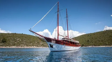 Romanca gulet with red hull and masts anchored in calm blue sea