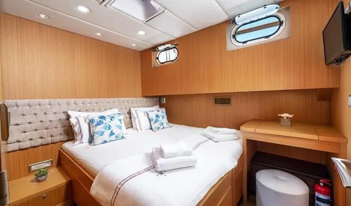 Artemis yacht cabin interior with bed, wood cabinetry, pillows, and ceiling hatch