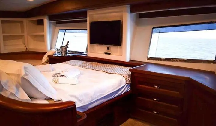 Master cabin with king bed, wood cabinetry, porthole windows, ensuite area
