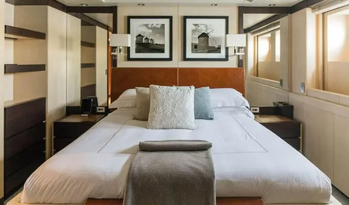 Master cabin with king bed, bedside lamps, framed photos above headboard