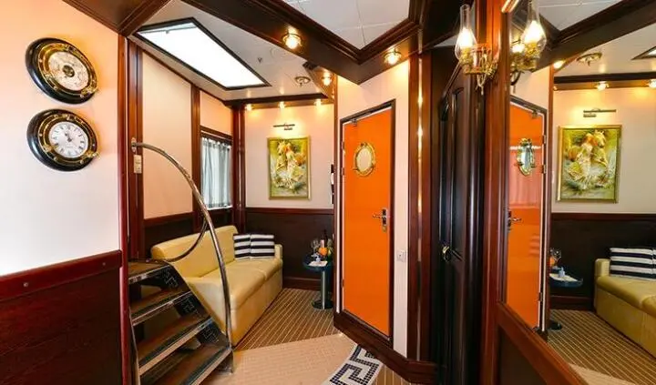 Cozy cabin interior of a yacht with wooden stairs, seating area, and warm lighting
