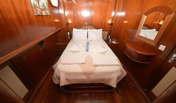 Master cabin with a large bed, wooden paneling, and neutral decor