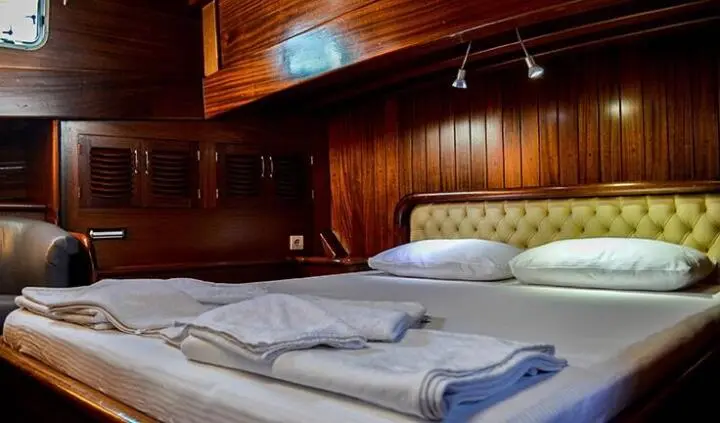 Luxurious yacht cabin with large bed, wood paneling, and soft lighting
