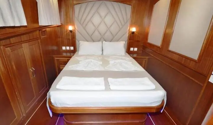 Prenses Esila cabin bed with white bedding and quilted headboard in wood-lined room
