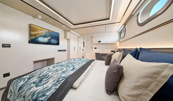 Master cabin with king bed, beige upholstery, blue throw pillows, ensuite area visible