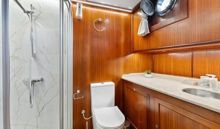 Small yacht cabin with wooden cabinetry, bed not visible, compact ensuite area