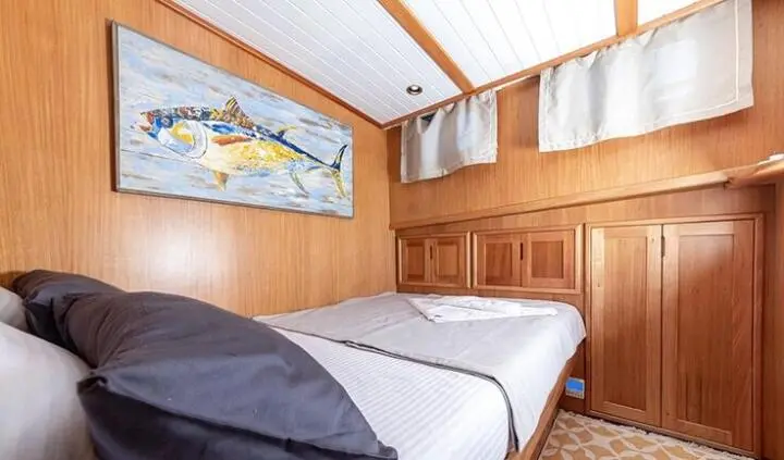Spacious master cabin with two twin beds pushed together, wooden walls