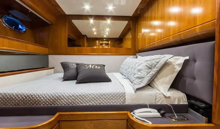 Master cabin with king bed, wood paneled walls, gray bedding, and ensuite door