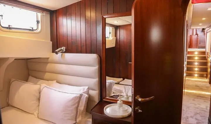 Interior of cabin with upholstered bed, wooden walls, and mirrored closet