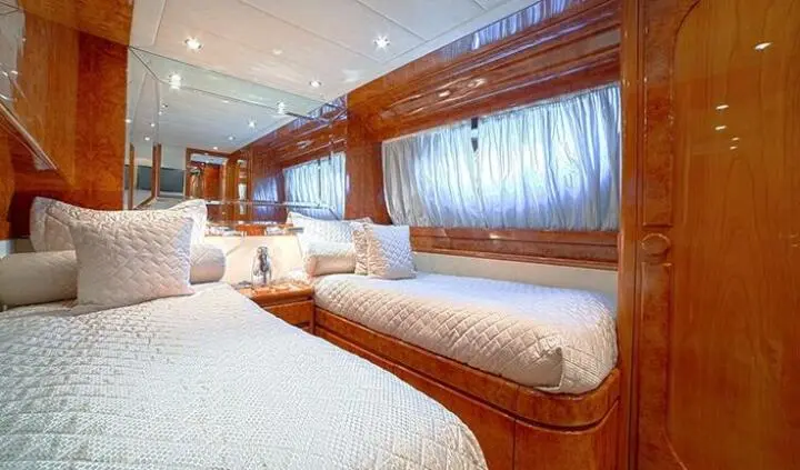 Twin cabin aboard Zoi yacht with wooden interior, two single bunks, porthole window