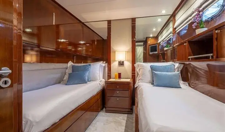 Two twin single beds in a cabin with blue pillows and wooden cabinetry