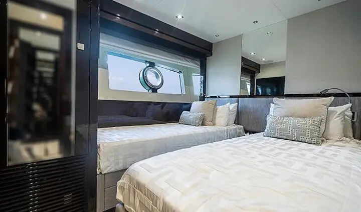Quantum yacht cabin interior with twin beds, plush pillows, and porthole window