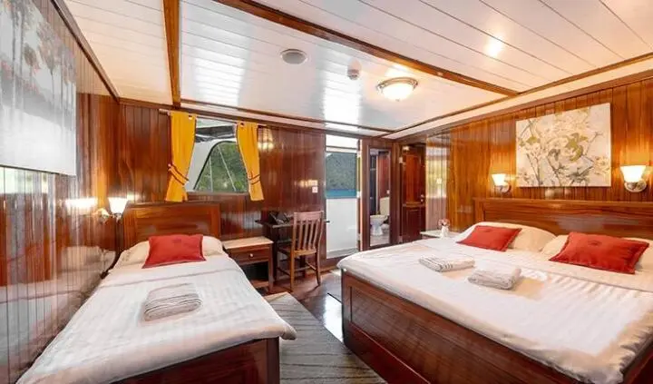 Cesarica yacht cabin interior with three beds, wood paneling, and warm lighting