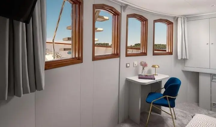 Cabin scene on Bellezza yacht with bed, dresser, and windowed wall view