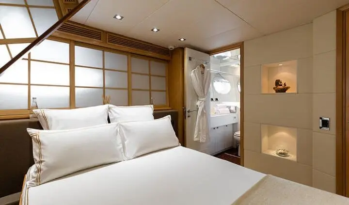 Twin beds in a yacht cabin with wood paneling and a doorway view