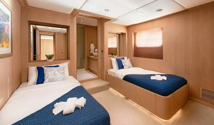 Grace yacht cabin interior with two blue beds, wooden panels, and towels