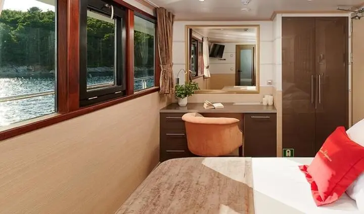 Queen Eleganza cabin interior with bed, vanity, and window view