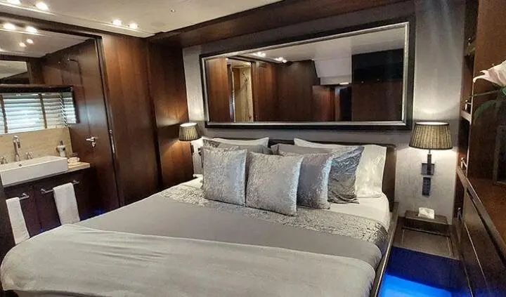Miraval master cabin bed with white linens and multiple pillows, wood features