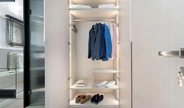 Master cabin wardrobe with hanging clothes, shelves, and slippers visible