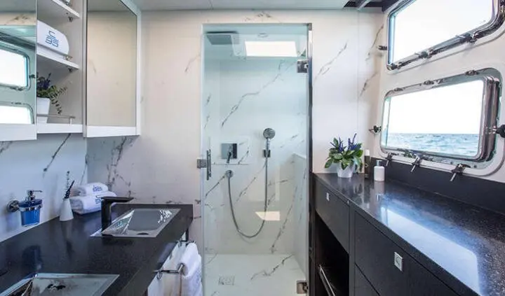 Master cabin with king bed and ensuite door visible through glass shower enclosure