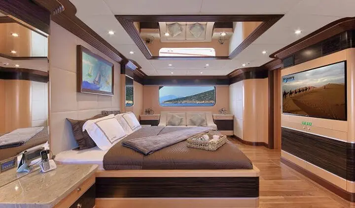 Master cabin with king bed, wood panels, and seating area aboard Meira yacht