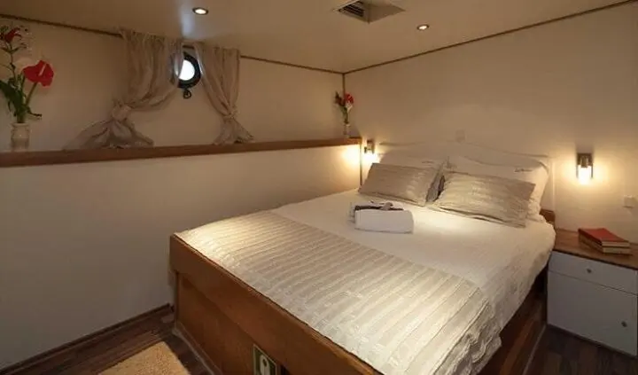Romanca yacht cabin with two single beds, wooden headboard, and pendant lights