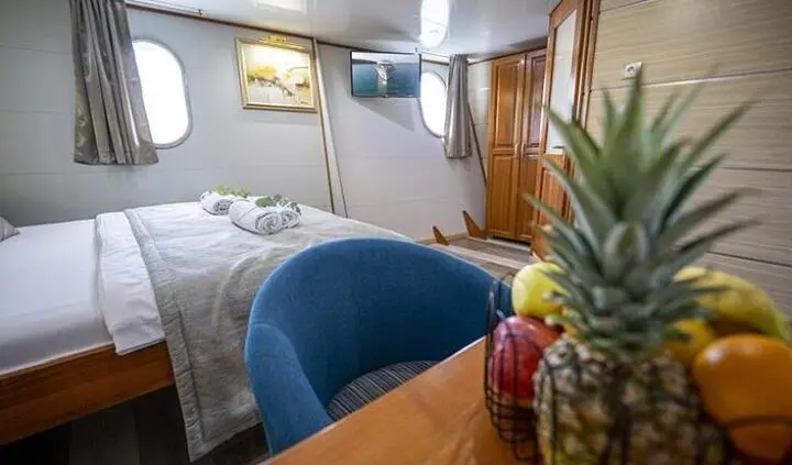 Master cabin with king bed, ensuite, blue upholstered headboard, portholes, wood cabinetry