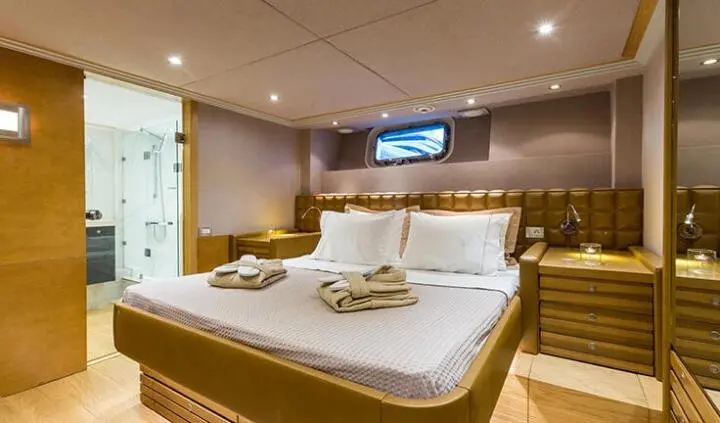 Master cabin with large bed, white linens, and ensuite bathroom visible